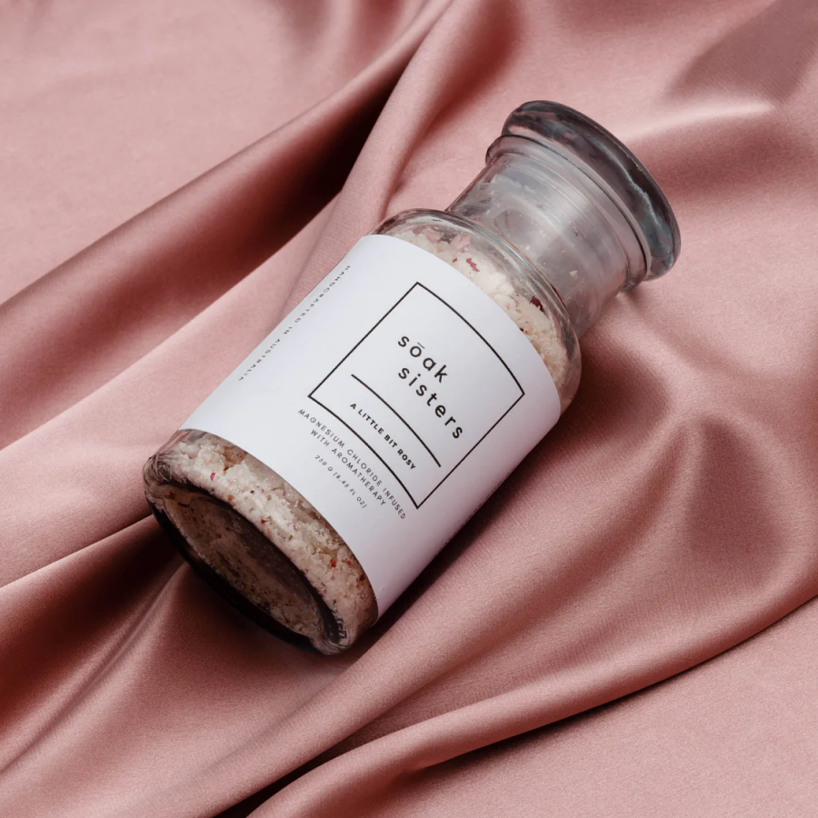 Bath salts jar laid on top of pink silk fabric