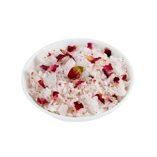 White dish filled with pink bath salts on white background