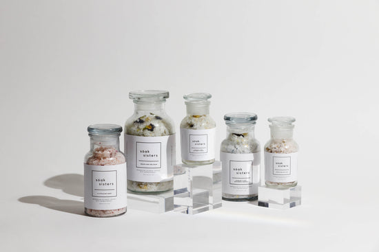 Five different sized bath salt jars on top of glass plinths at different heights